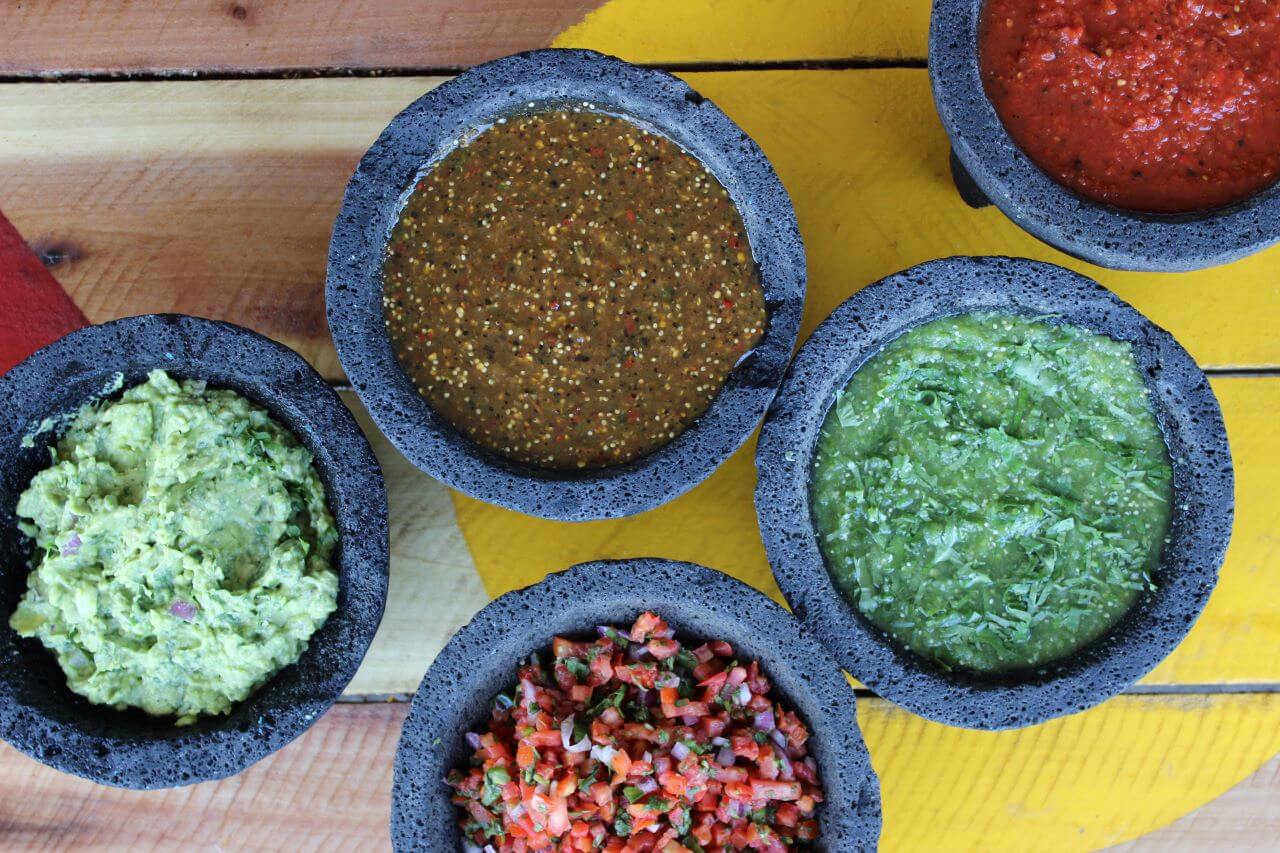 A top view of a bunch of Bowls of salsas and sauces